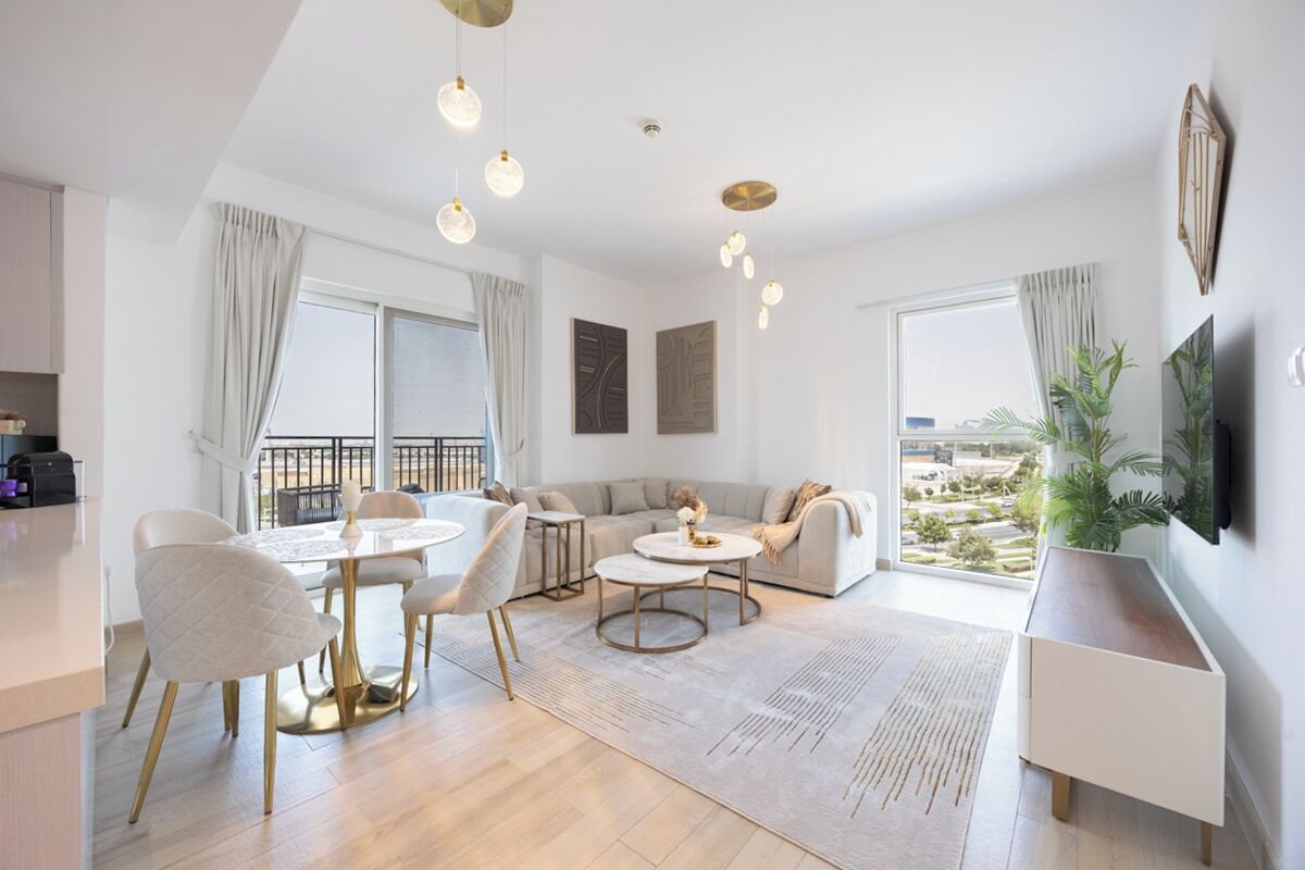 Un salon moderne comprenant un coin repas, un canapé, un téléviseur fixé au mur et un balcon avec vue.