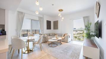 En moderne stue med spiseplads, sofa, fjernsyn monteret på væggen og en balkon med udsigt.