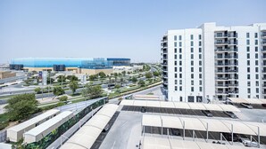 A modern building with multiple floors and balconies, surrounded by a parking area and greenery. - Bloomfields 3BR plus maid in Waters Edge (Abu Dhabi)