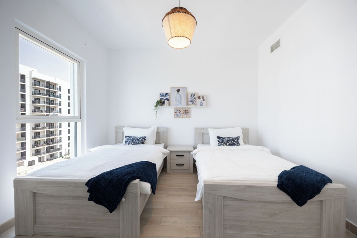 Quarto com duas camas, uma janela e um lustre.