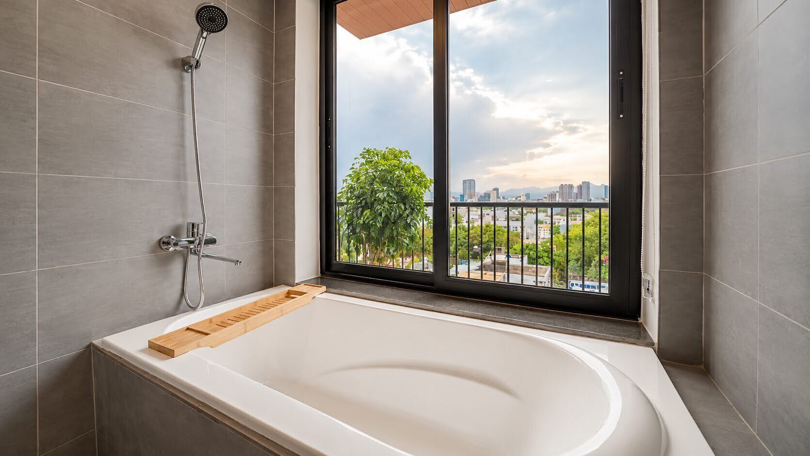 Une salle de bain moderne équipée d’une baignoire, d’une douche et d’une fenêtre donnant sur la ville.
