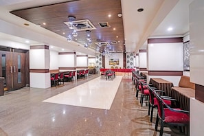 A spacious hall with rows of tables and chairs, a polished floor, and a ceiling with recessed lighting. - Townhouse Rajkot Bus Stand (Rajkot)