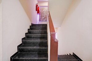 A staircase with black steps and a brown handrail leading to a landing.