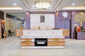 A reception desk with a marble top, a clock, and a Buddha statue above it. - Townhouse Rajkot Bus Stand (Rajkot)