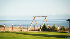 A swing set in a grassy area with a view of the sea.