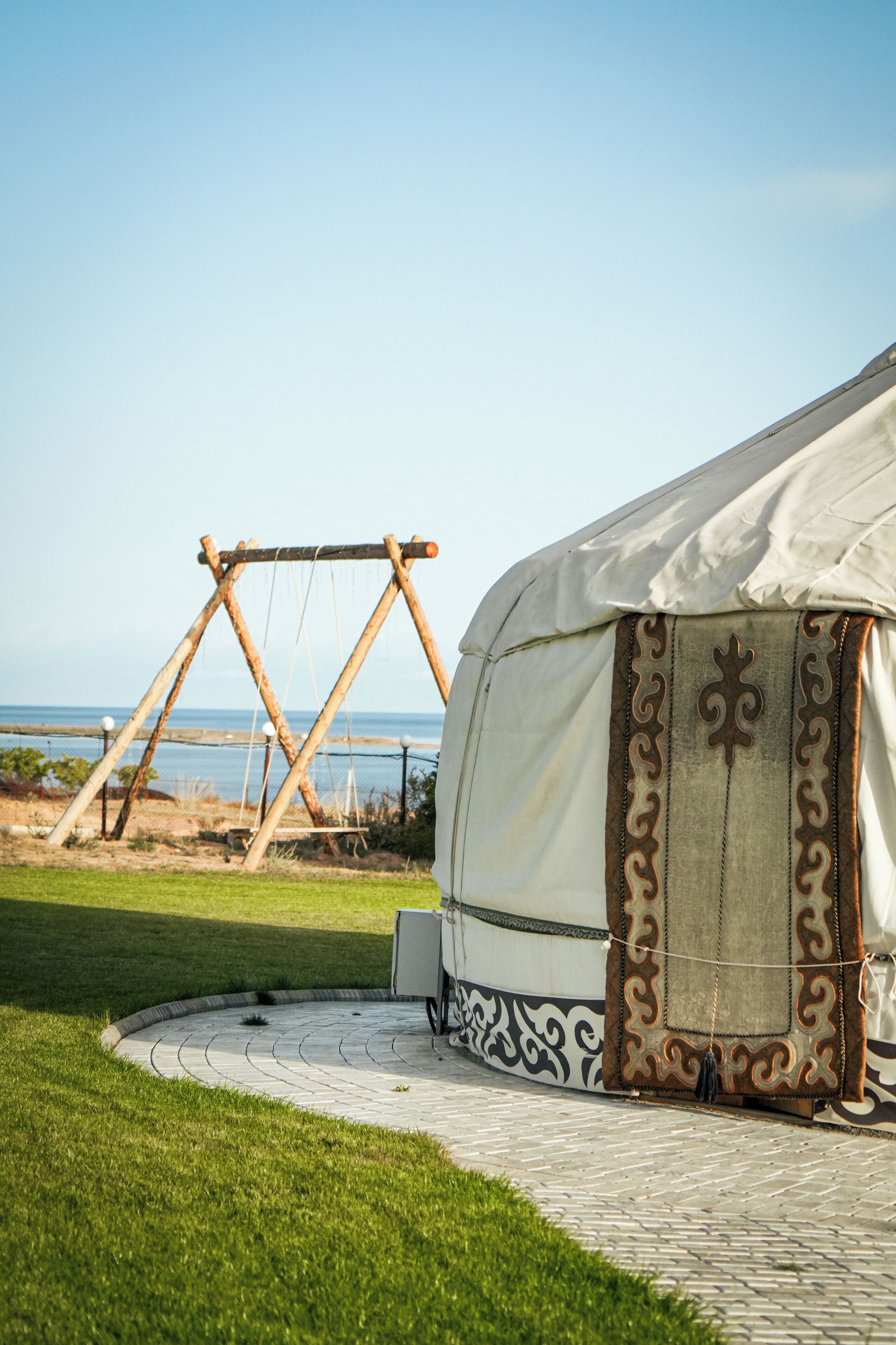Una tenda amb una entrada amb dibuixos, un tobogan i un camí pavimentat que condueix a una zona verda amb vista al mar.