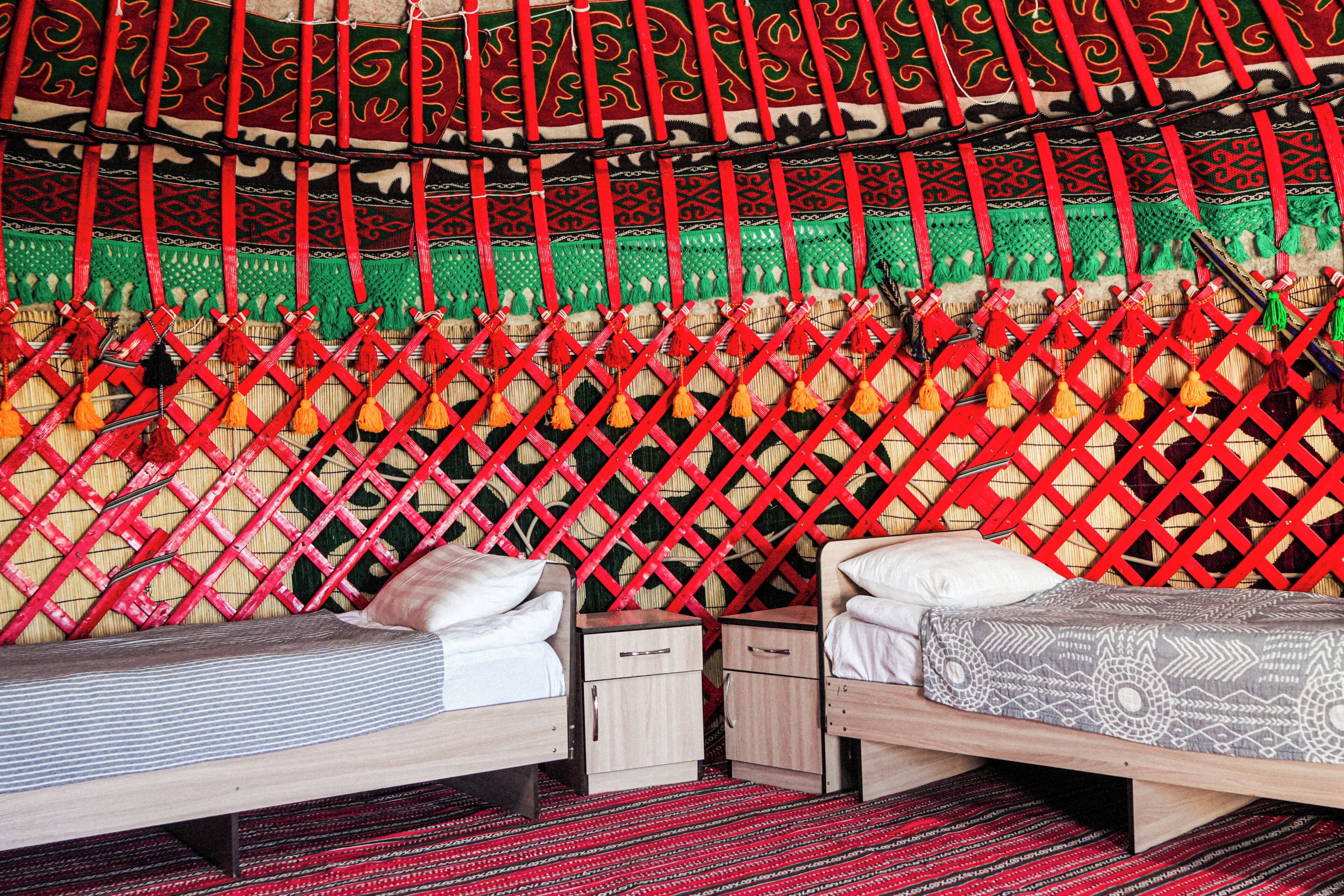 Ein Zimmer mit zwei Betten, einer gewebten Wandstickerei und einem gemusterten Boden.