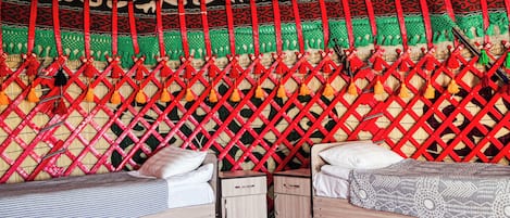 A room with two beds, a woven wall tapestry, and a patterned floor.