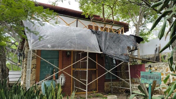 Un edificio con techo parcialmente derrumbado, rodeado de andamios y materiales de construcción.
