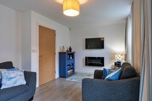 Ein modernes Wohnzimmer mit Fernseher, einer blauen Unterhaltungseinrichtung und zwei grauen Sofas.