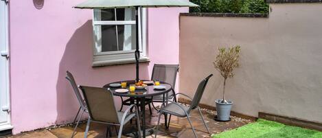 An outdoor patio with a table, chairs, and a potted plant.