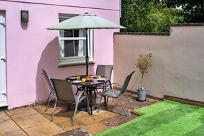 Eine Terrasse im Freien mit Tisch, Stühlen und einem Blumentopf.
