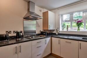 Une cuisine moderne équipée d’une cuisinière à gaz, d’une bouilloire et d’une machine à café.