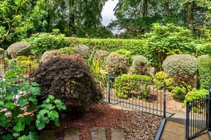 A well-maintained garden with various shrubs and a metal fence. - Marshmallow House (Duporth)
