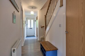 A hallway with a wooden bench, a radiator, and a door at the end. - Marshmallow House (Duporth)