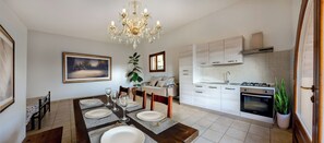A dining area with a chandelier, a painting, and a view of the kitchen. - 6-BED AGRITOURISM COTTAGE WITH VERANDA AND AIR-CONDITIONED GARDEN (Toscana)