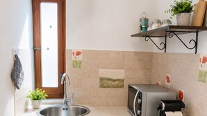 Een praktische keuken met een spoelbak, fornuis, broodrooster en een klein raam.