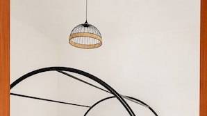 Een bed met een zwart metalen frame en witte beddengoed, twee nachtkastjes met lampen, en een hangende lamp.