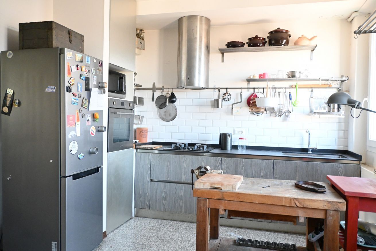 A kitchen with a refrigerator, microwave, stove, and wooden table.