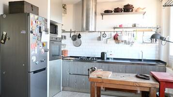 A kitchen with a refrigerator, microwave, stove, and wooden table.