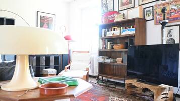 A living room with a television, bookshelves, a lamp, and a patterned rug.