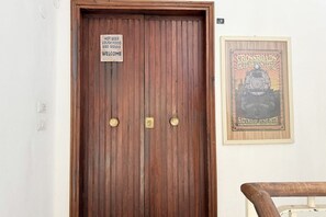 A wooden door with a sign indicating hot beer, lousy food, and bad service, and a framed poster for the Crossroads Guitar Festival.