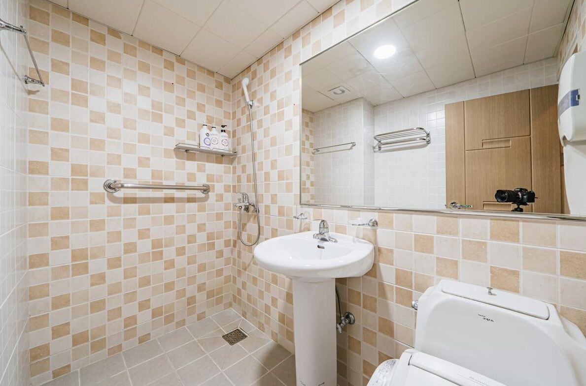 Un baño con suelo de baldosas a cuadros, un lavabo blanco, un espejo y un inodoro.