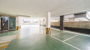 Un estacionamiento con pilares de concreto, piso verde y un letrero que indica Hotel 5.