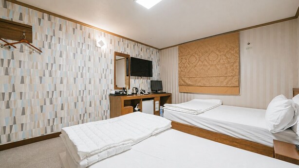 Habitación de hotel con dos camas, un televisor, un escritorio con computadora y un espejo.