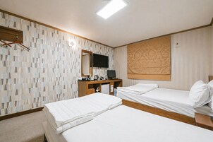 A hotel room with two beds, a TV, a desk with a computer, and a mirror.
