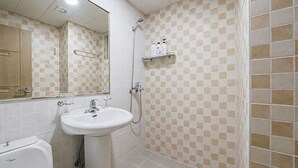 Un baño con lavamanos blanco, espejo, ducha y pared con azulejos.