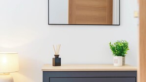 Quarto moderno com um armário de madeira, um espelho, uma pequena planta em vaso e uma luminária.