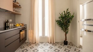 A kitchen with a modern design, featuring a built-in oven, a countertop with a fruit bowl, and a potted plant. - ALL Savoia Station – Elegance, Relax & Comfort in the Heart of Bari (Bari)