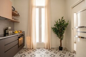 A kitchen with a modern design, featuring a built-in oven, a countertop with a fruit bowl, and a potted plant. - ALL Savoia Station – Elegance, Relax & Comfort in the Heart of Bari (Bari)