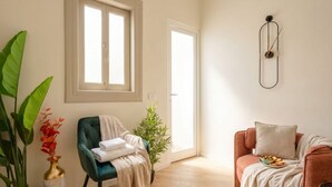 A room with a window, a chair, a sofa, a wall clock, and a plant. - ALL Savoia Station – Elegance, Relax & Comfort in the Heart of Bari (Bari)