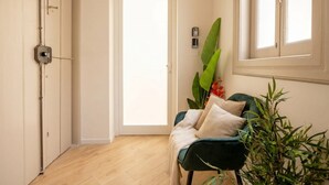 A hallway with a door, a plant, and a chair. - ALL Savoia Station – Elegance, Relax & Comfort in the Heart of Bari (Bari)