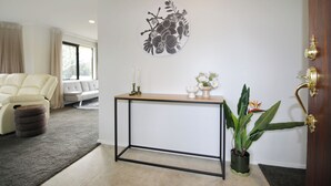 Ein stilvolles Wohnzimmer mit einem weißen Sofa, einem Konsolentisch mit Pflanze und einem Wandbild.