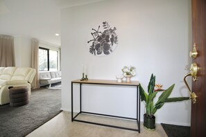 Ein stilvolles Wohnzimmer mit einem weißen Sofa, einem Konsolentisch mit Pflanze und einem Wandbild.