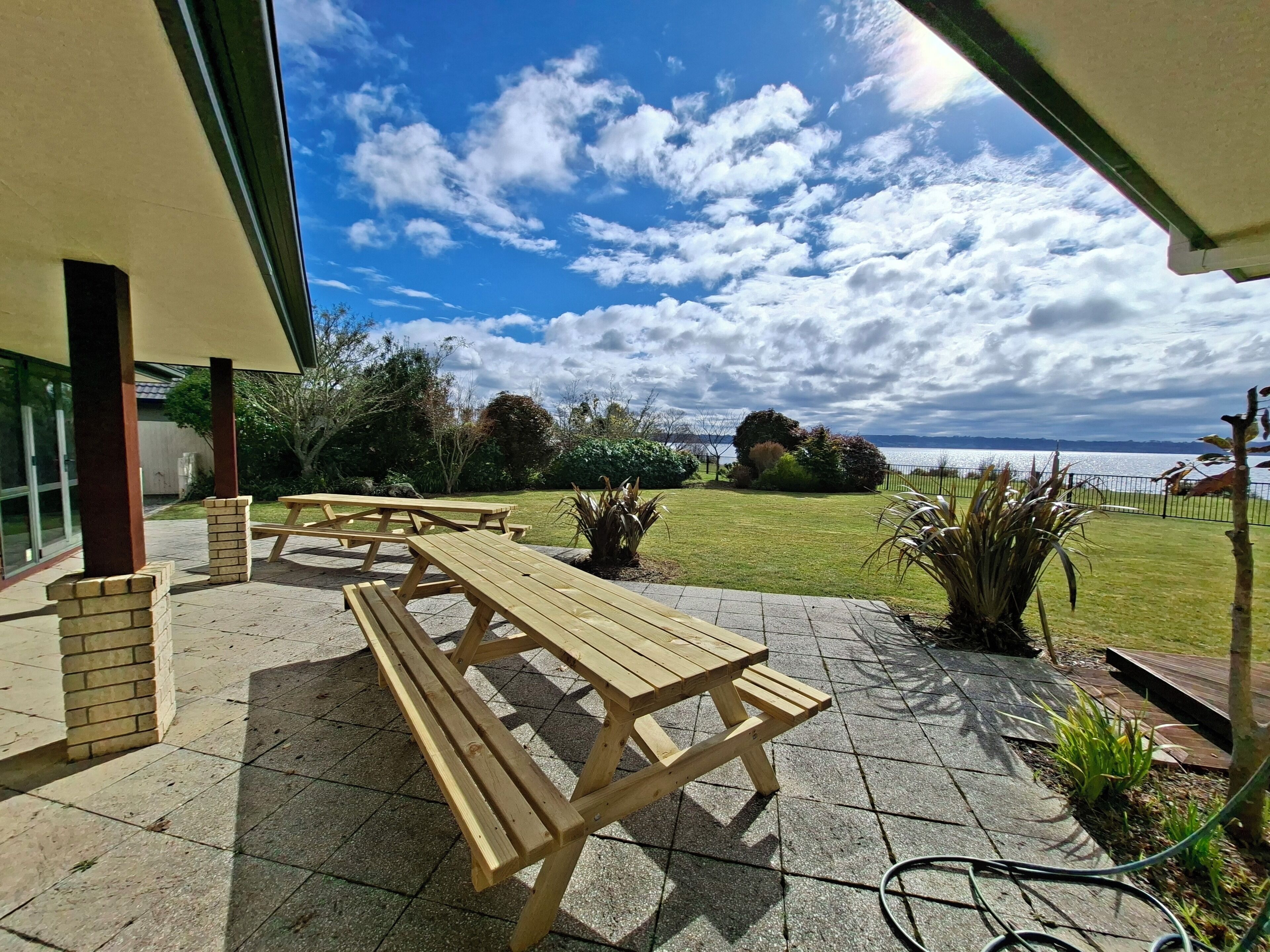 An outdoor patio with wooden benches and a view of the water.