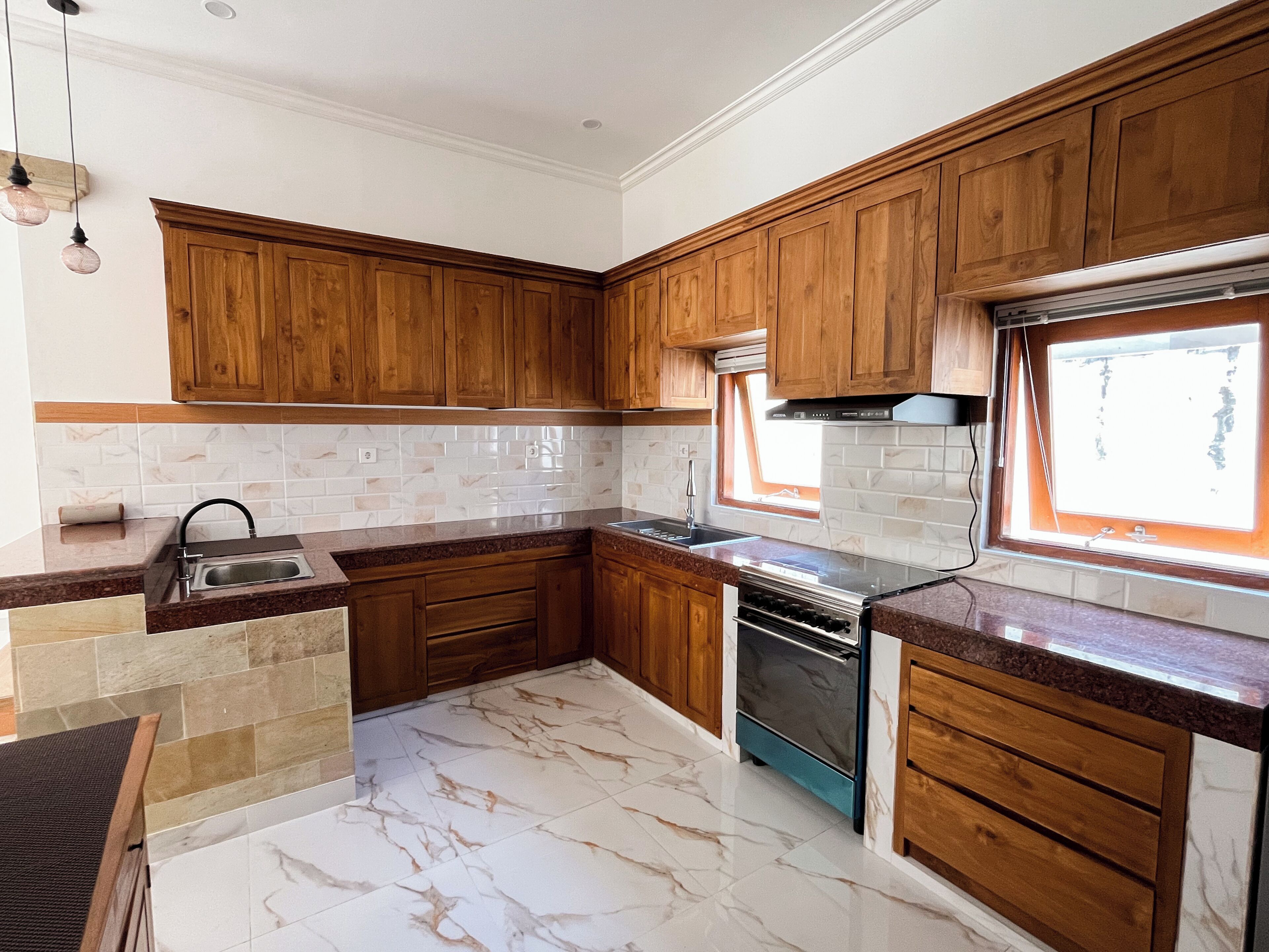 A kitchen with wooden cabinets, a built-in oven, and a window.