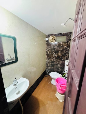 Un baño con lavamanos, inodoro, ducha y espejo.