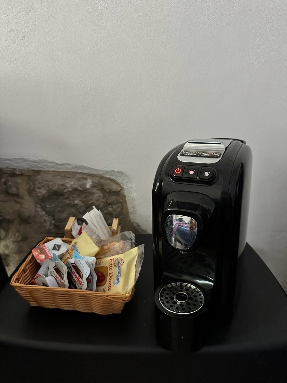 A coffee machine with a basket of assorted snacks and a small wooden box.