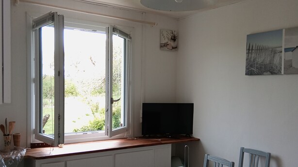 A small kitchen with a window, a table, and a television.