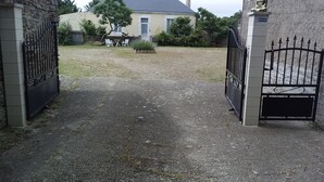 A gated entrance to a property with a gravel driveway leading to a building with a tiled roof.