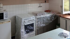 A kitchen with white cabinets, a microwave, and a sink covered in plastic.