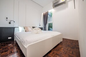 Habitación de hotel con una cama grande, una ventana con cortinas, un equipo de aire acondicionado y una lámpara fijada a la pared.