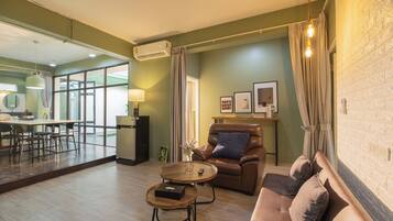 A modern living room with a sofa, a coffee table, and a dining area with a table and chairs.