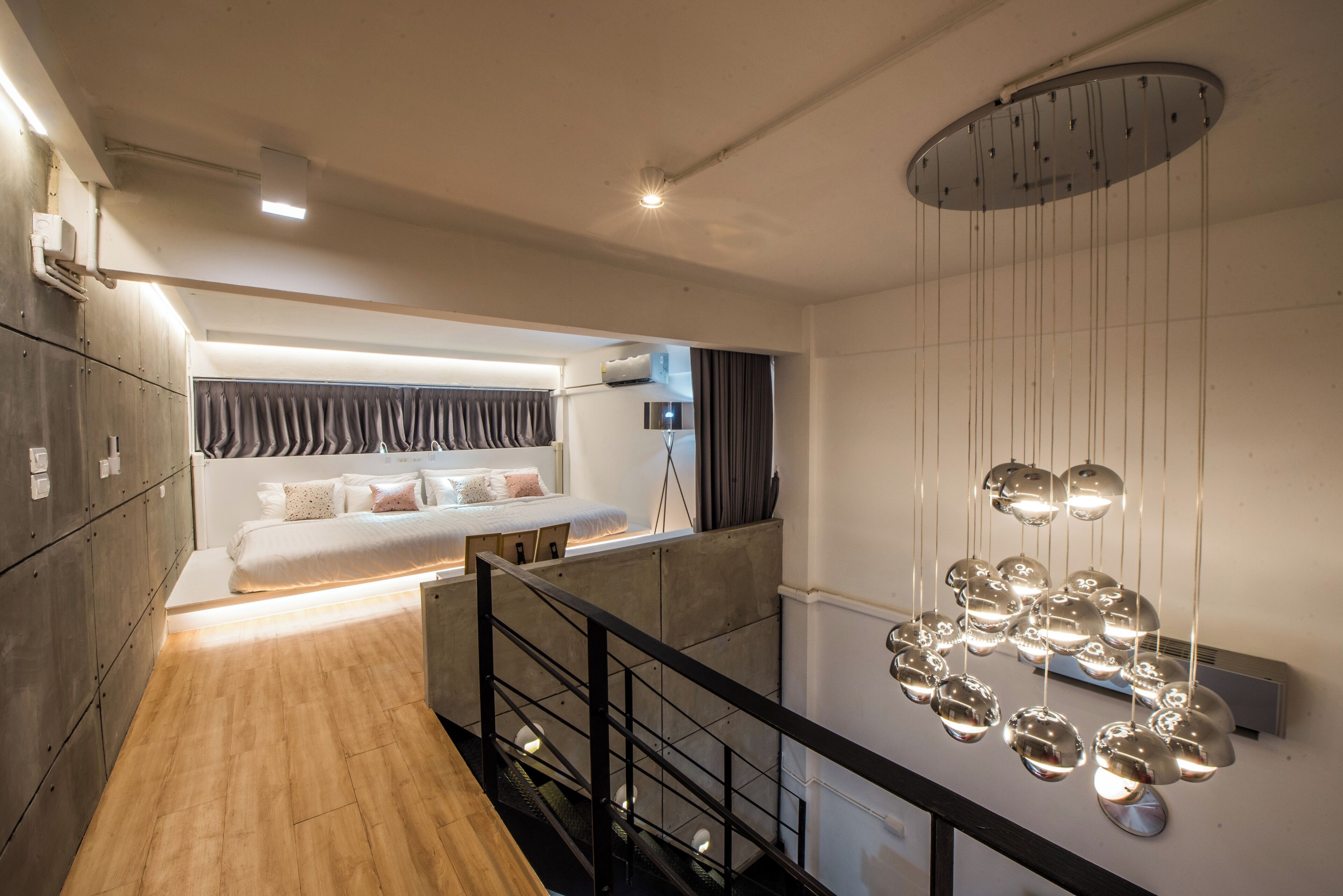Een moderne hotelkamer met een bed, een inbouwkleerkast en een trap met een leuning.
