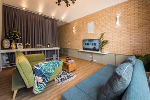 Una sala de estar moderna con sofá, una mesa de centro, un televisor y una pared de ladrillo.