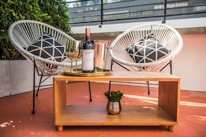 Una mesa de madera con una botella de vino, dos copas y una bandeja encima.
